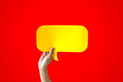 Human Hands Holding Yellow Speech Bubble Over Red Background - Balloon speech bubble concept