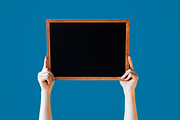 Human Hands Holding Empty Blank Black Board Over Blue Background - Ready for adding your text here