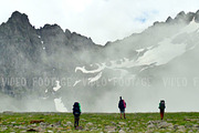Group of tourists with Hiking backpacks coming in High Spring Mountains with Clouds