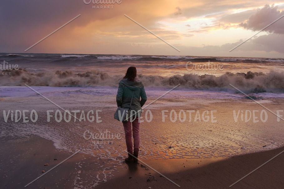 silhouette of a girl. she looks at storm sea in sunset time. waves reach up to her feet in Graphics - product preview 8