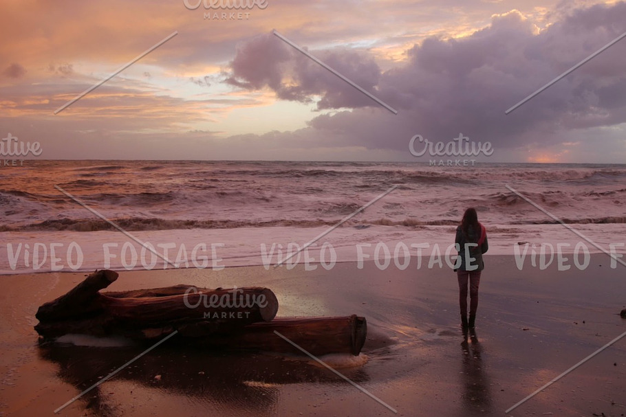 silhouette of a girl. she looks at storm sea in sunset time. waves reach up to her feet in Graphics - product preview 8