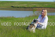 Pretty girl plays with a dog on the grass by the lake nature animals pets friend emotions happy smile dog slow motion lake sky clouds sun evening sunset girl with a dog in the sunset beach water