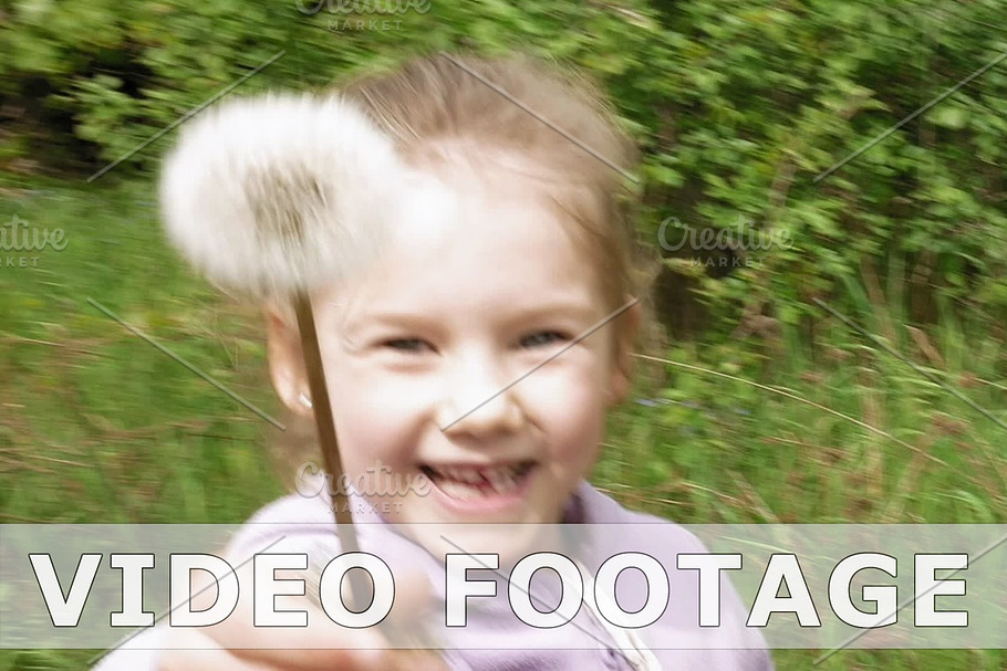 Smiley little girl blows off dandelion and laughs