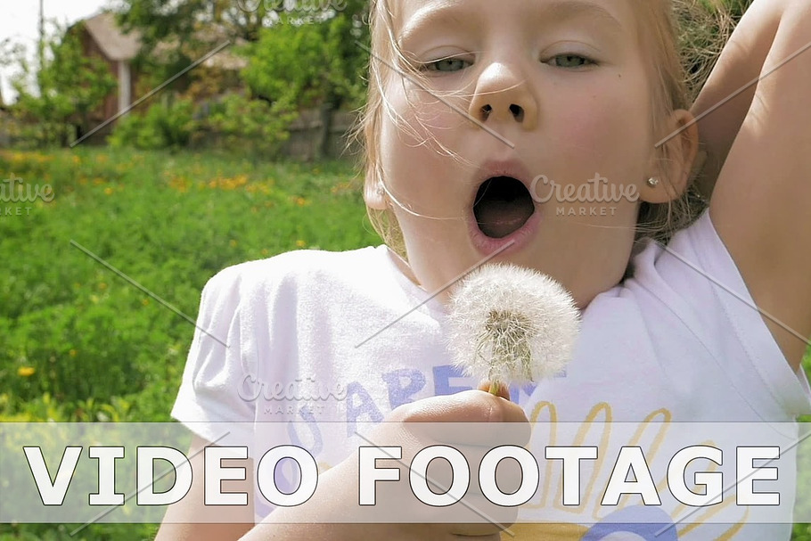 Smiley little girl blows off dandelion and laughs