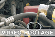 Auto mechanic pours additional motor engine oil