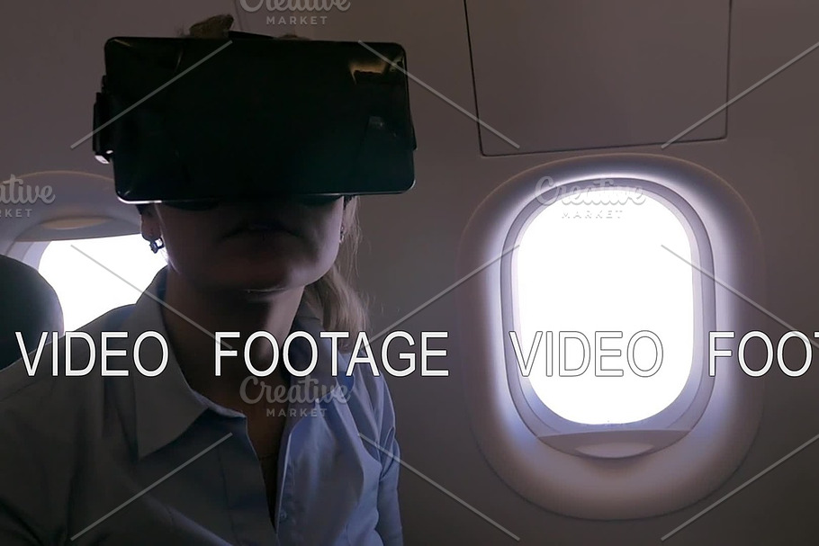 Slow motion view of woman using VR-helmet for smartphone in airplane