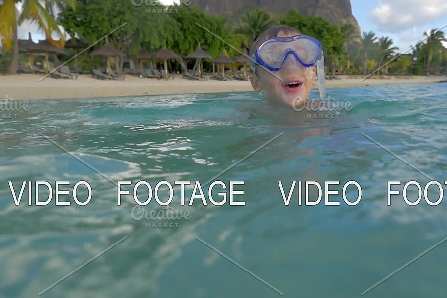 Slow motion view of small boy swimming in the Indian Ocean in the snorkeling mask and take a picture, Port Louis, Mauritius Island