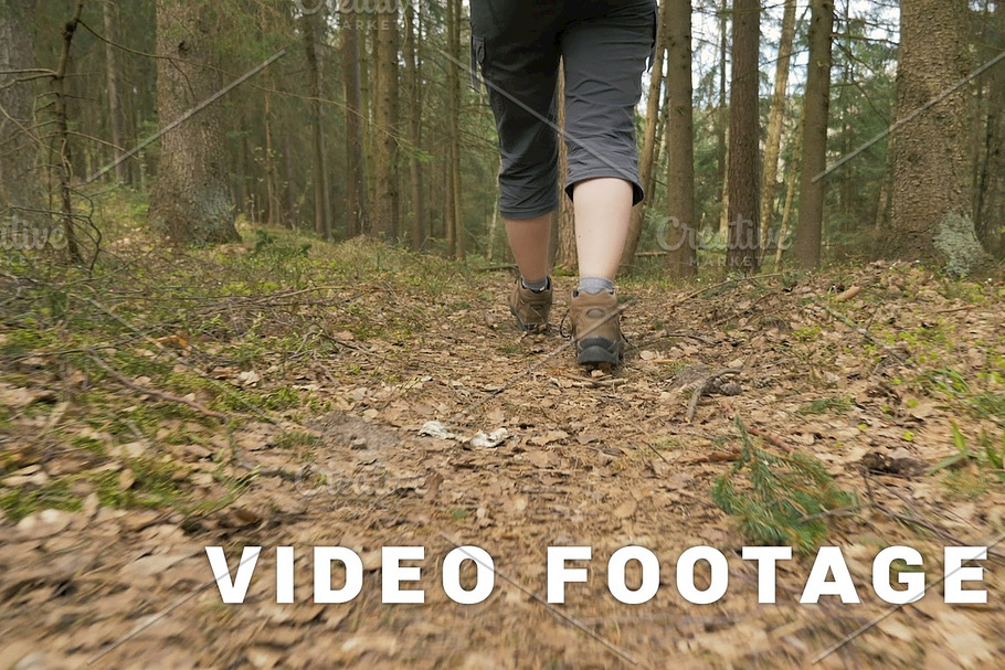 Legs of the young girl with backpack in the summer forest - flying camera shot