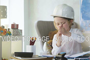 small kid boy in white helmet imitates constructor working and busy man