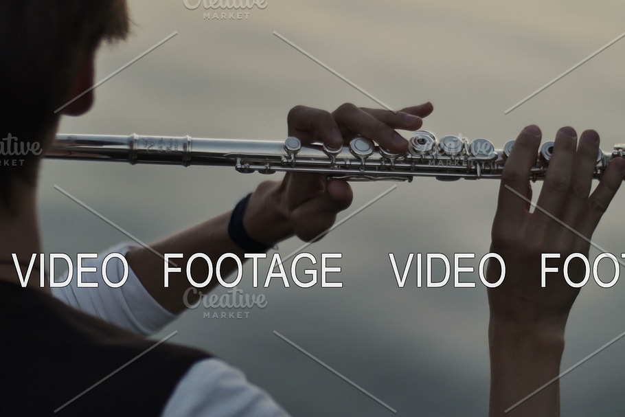 closeup of flutist playing in the sunset near water