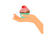 Hand holding cupcake with two hearts