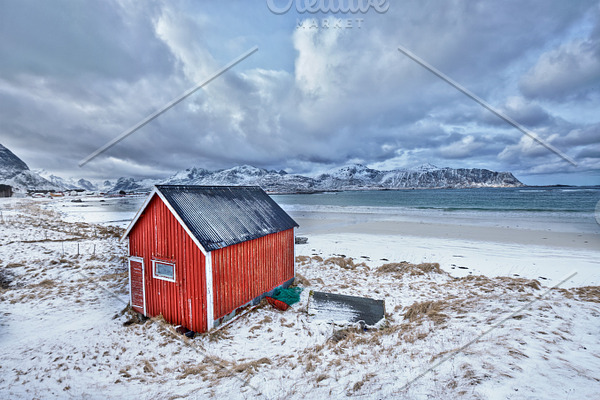 Red rorbu house shed on beach of fjord, Norway