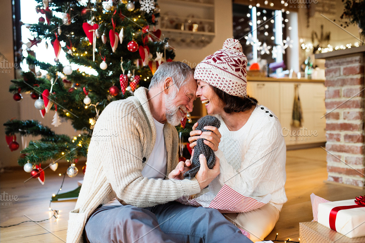Senior couple in front of Christmas tree enjoying presents. in Graphics - product preview 8