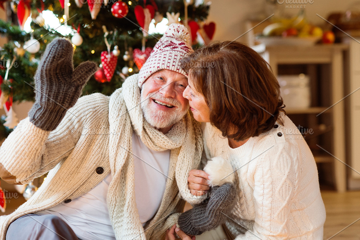 Senior couple in front of Christmas tree enjoying presents. in Graphics - product preview 8