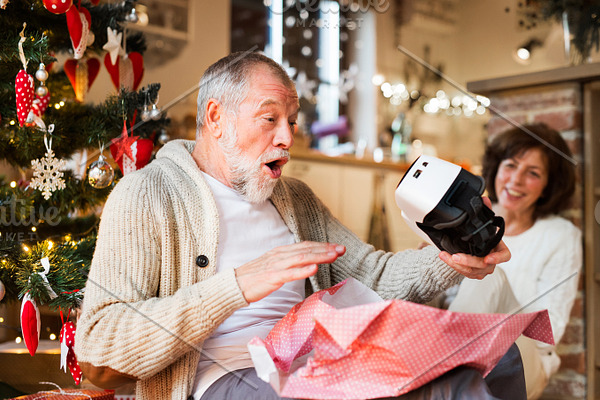 Senior couple in front of Christmas tree with VR goggles.
