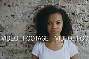 Portrait of curly african american teenager girl actively surprising and wondering on brick wall background