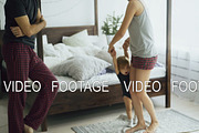 Happy family and little cute daughter dancing and turning around near bed in bedroom at home