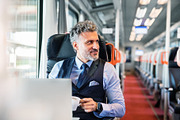 Mature businessman with laptop travelling by train.