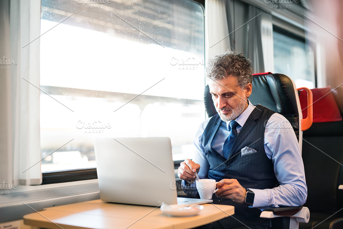 Mature businessman with laptop travelling by train. in Graphics - product preview 8
