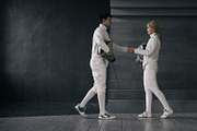 Two fencers man and woman shake hands each other at the end of fencing competition indoors