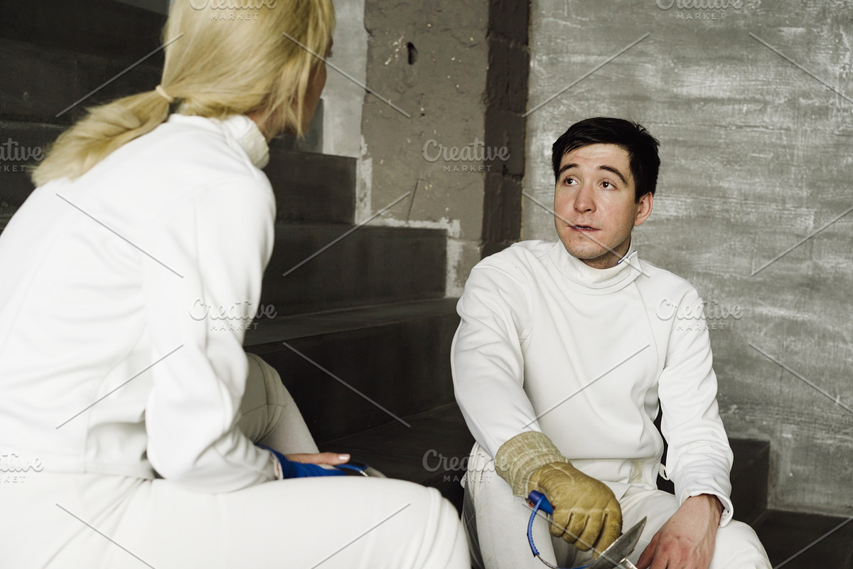 Two fencers man and woman sharing experience during break of fencing match indoors in Graphics - product preview 8