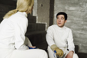 Two fencers man and woman sharing experience during break of fencing match indoors