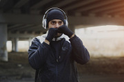 Young man boxer in headphones training punches in urban location outdoors in winter