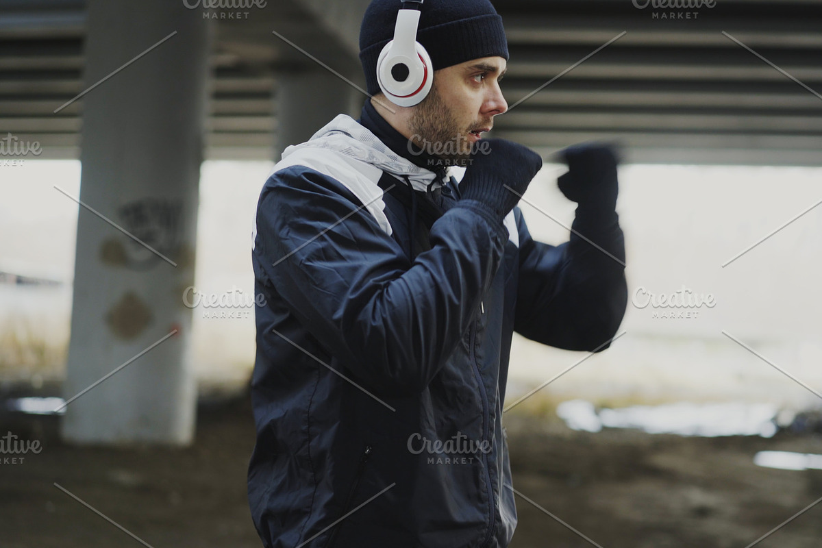 sportive man boxer in headphones doing boxing exercise in urban location outdoors in winter in Graphics - product preview 8