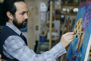 Concentrated man artist painting still life picture on canvas in art studio indoors
