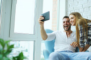 Young attractive couple having online video chat using tablet computer sitting at balcony in modern loft apartment