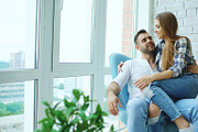 Beautiful young couple relax sitting on chair and enjoying view from balcony of new loft apartment