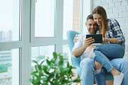 Young cheerful couple talking and using tablet computer on balcony in modern loft apartment