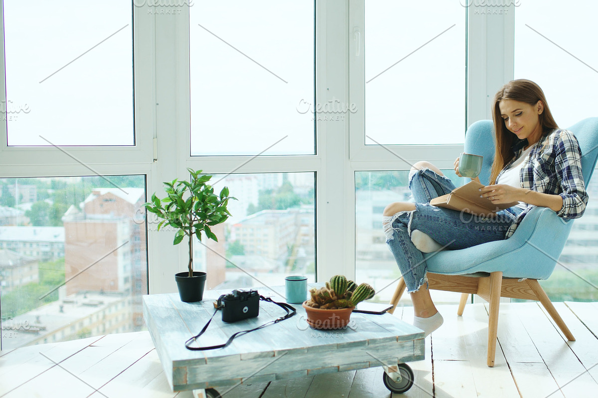 Young attractive woman read book and drink coffee sitting on balcony in modern loft apartment in Graphics - product preview 8