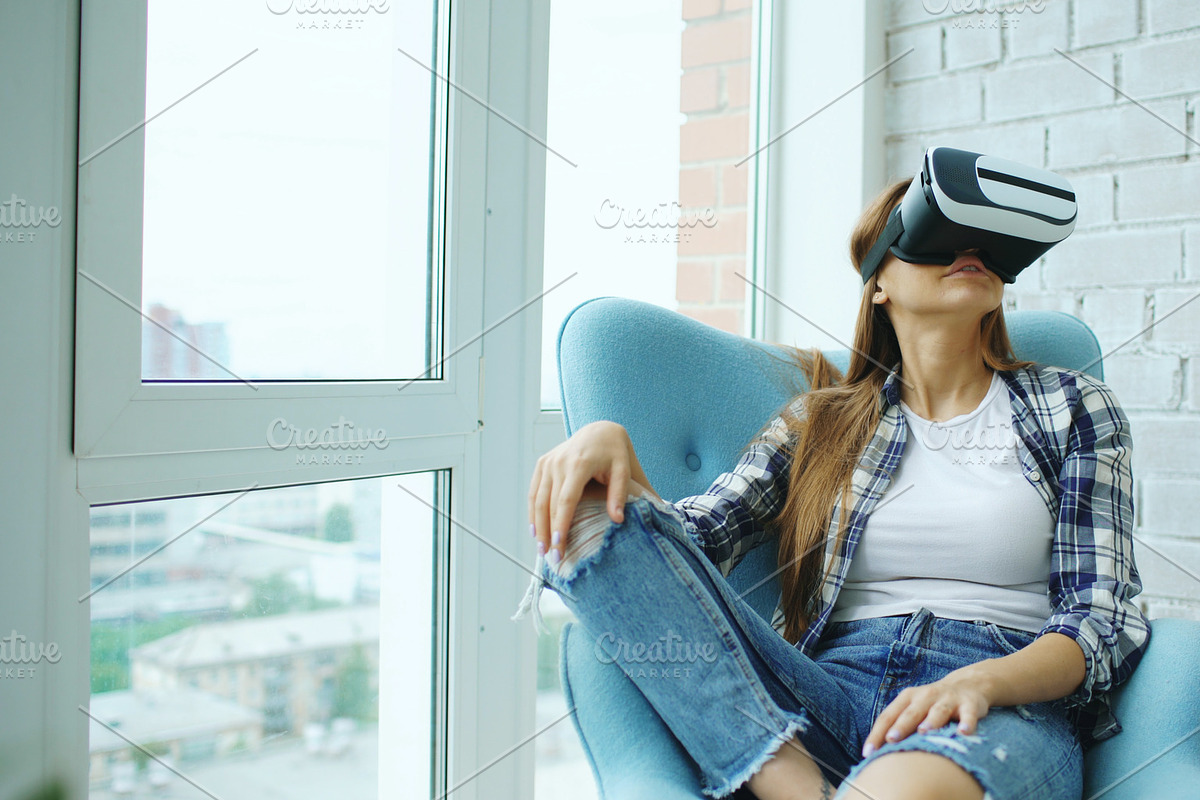 Young woman have VR experience using virtual reality headset sitting in chair on balcony in Graphics - product preview 8