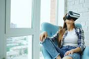 Young woman have VR experience using virtual reality headset sitting in chair on balcony