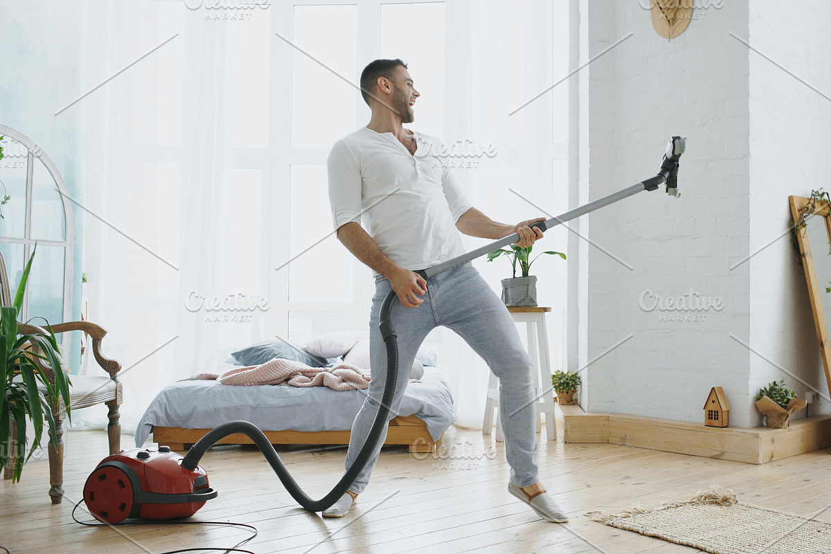 Young man having fun cleaning house with vacuum cleaner dancing like guitarist in Graphics - product preview 8