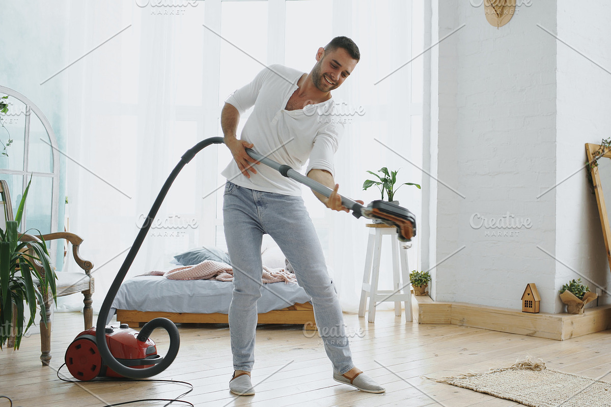 Young man having fun cleaning house with vacuum cleaner dancing in Graphics - product preview 8