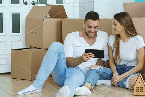 Young couple sitting on floor using tablet computer after reloction in their new home