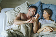 Top view of young couple lying in bed upset and argue each other