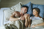 Top view of young couple lying in bed and talking each other smiling