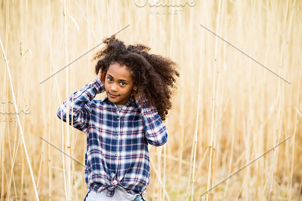 African american girl in checked shirt outdoors in field.