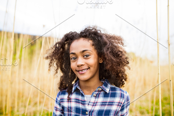 African american girl in checked shirt outdoors in field.