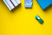 Gift boxes and toy car on yellow background