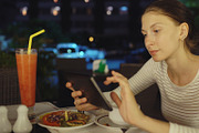 Happy woman using smartphone and messaging sitting in restaurant at night