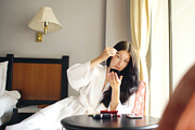 Bathrobe happy woman sitting on chair and making makeup herself in hotel room