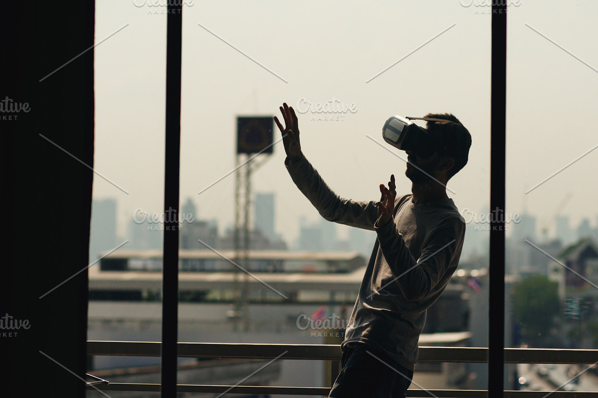 Silhouette of young man watching movie in VR headset and have virtual reality experience on hotel room balcony in Graphics - product preview 8