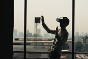 Silhouette of young man watching movie in VR headset and have virtual reality experience on hotel room balcony