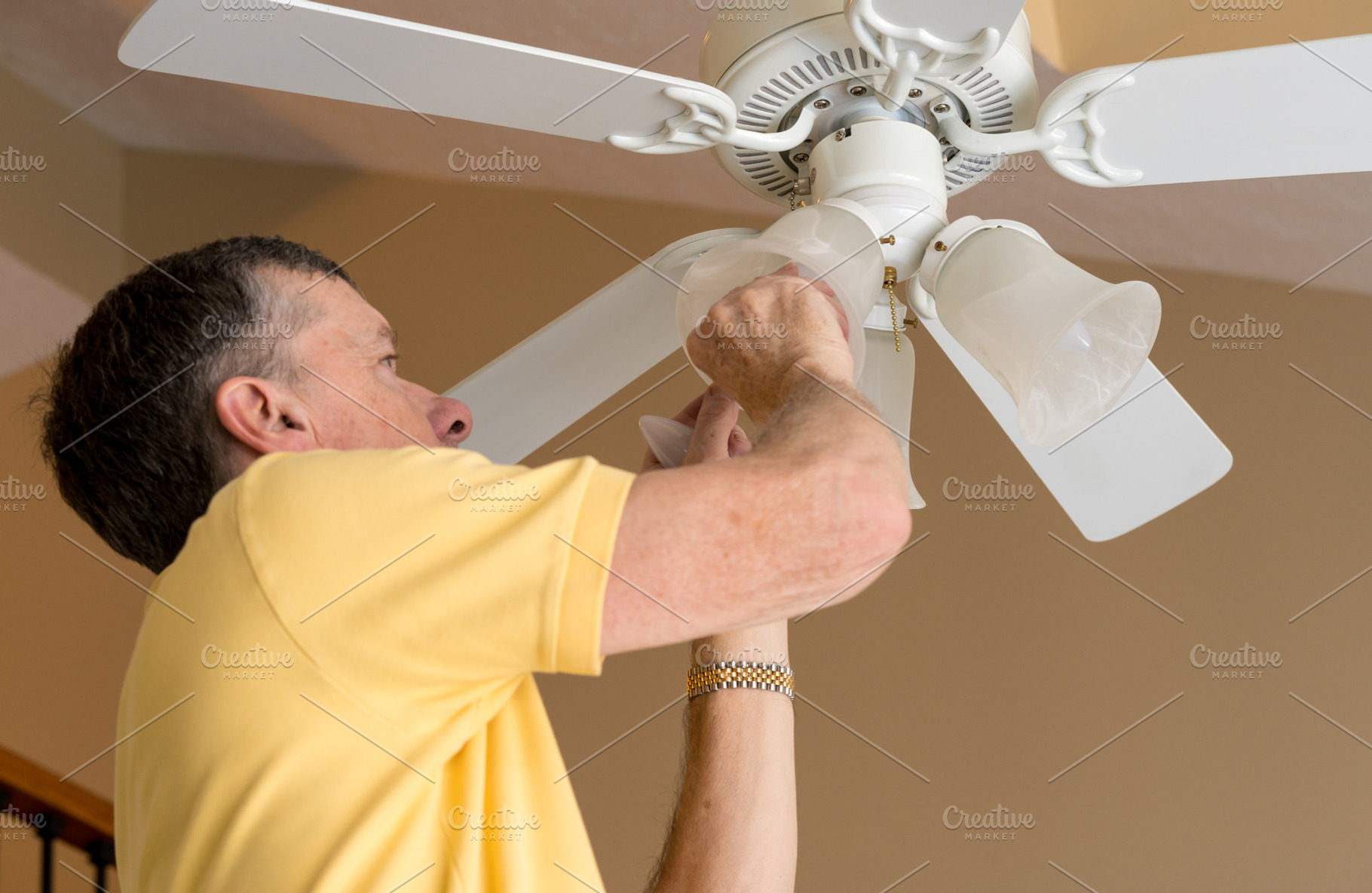 Senior Caucasian Man Replacing Bulb In Ceiling Fan And Light