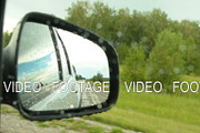 Reflection of side-view mirror of car driving in the countryside on rainy day