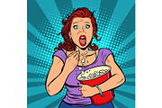 Woman watching a scary movie and eating popcorn